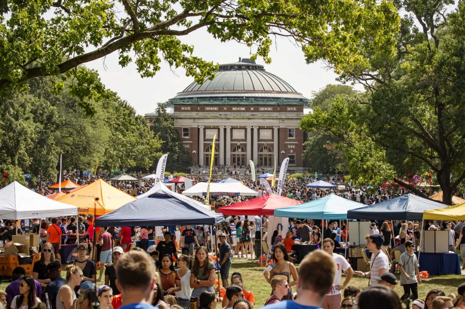 masses of students visit tents on Quad Day with Foellinger Auditorium in background