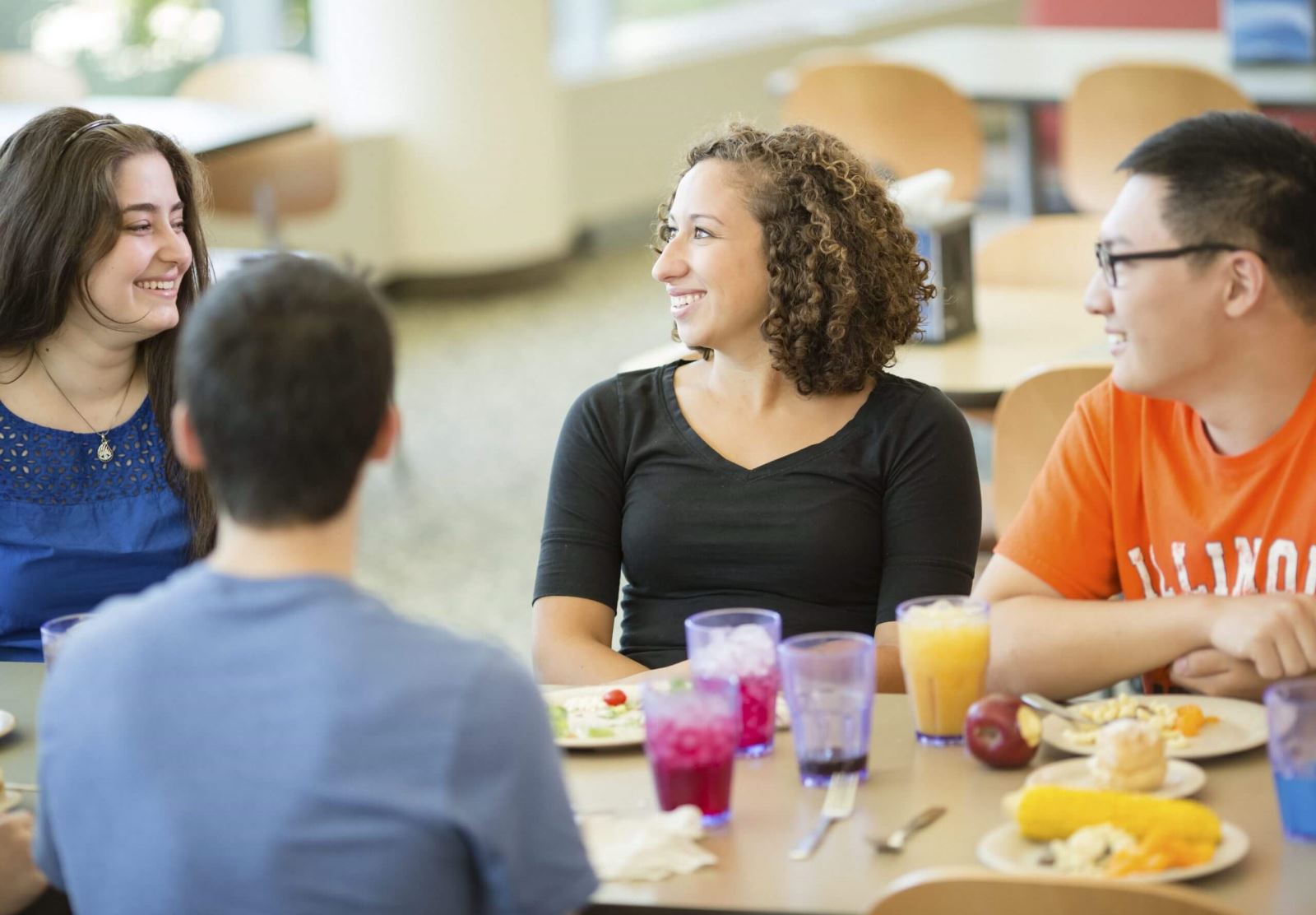 Students chatting while eating at table in dining hall