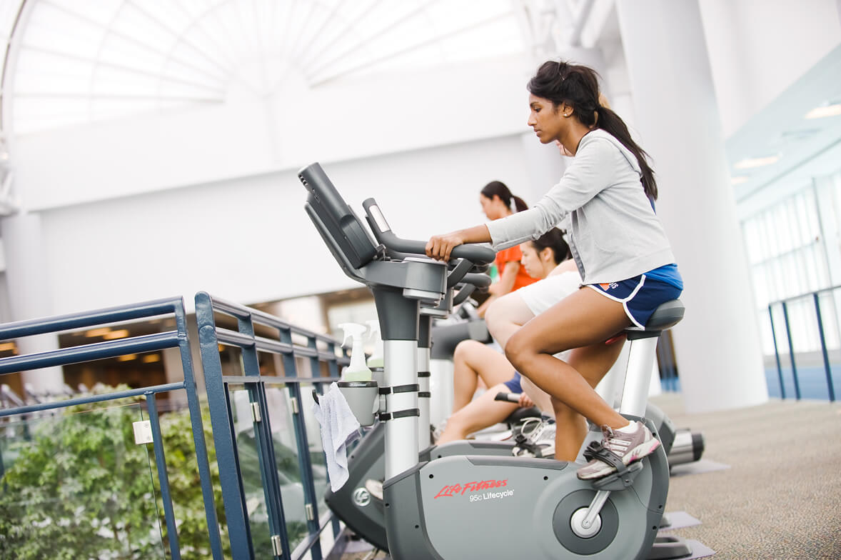 Female students working out on seated stationary bikes
