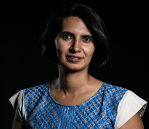 A person with short dark hair wearing a blue and white dress